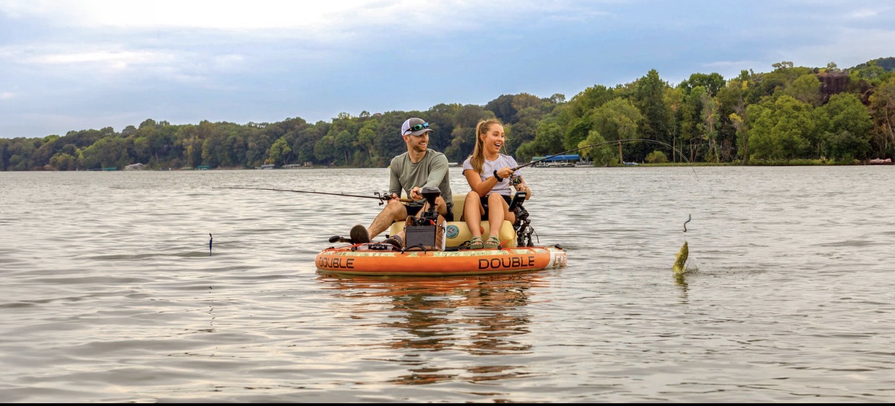 Two anglers fishing from an orange Double GoBoat on calm open water